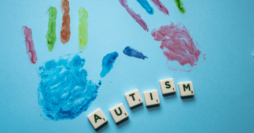 Colored handprints over blocks that spell out the word "Autism".